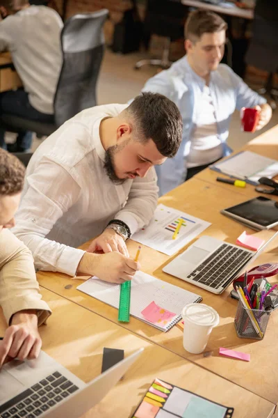 Jeunes collègues caucasiens travaillant ensemble dans un bureau en utilisant des appareils et des gadgets modernes — Photo