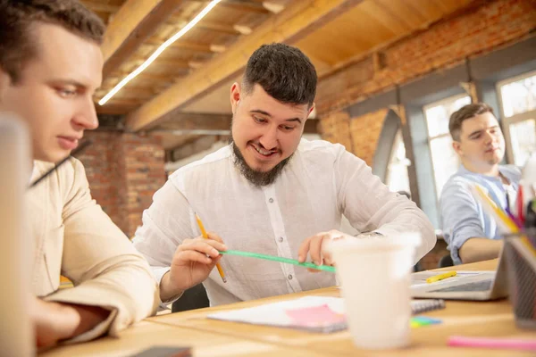 Jeunes collègues caucasiens travaillant ensemble dans un bureau en utilisant des appareils et des gadgets modernes — Photo