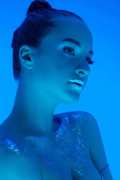 Knappe vrouwen portret geïsoleerd op blauwe studio achtergrond in neon licht, monochroom — Stockfoto