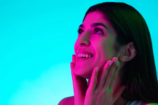 Morena bela mulher retrato isolado no estúdio azul fundo em luz de néon multicolorido — Fotografia de Stock