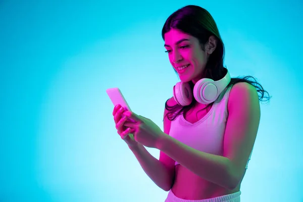 Morena bela mulher retrato isolado no estúdio azul fundo em luz de néon multicolorido — Fotografia de Stock