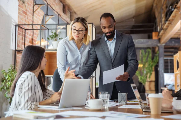 Diverso grupo de compañeros de trabajo que tienen una discusión informal en el cargo. Ejecutivos durante la discusión amistosa, informes mensuales, reunión creativa —  Fotos de Stock