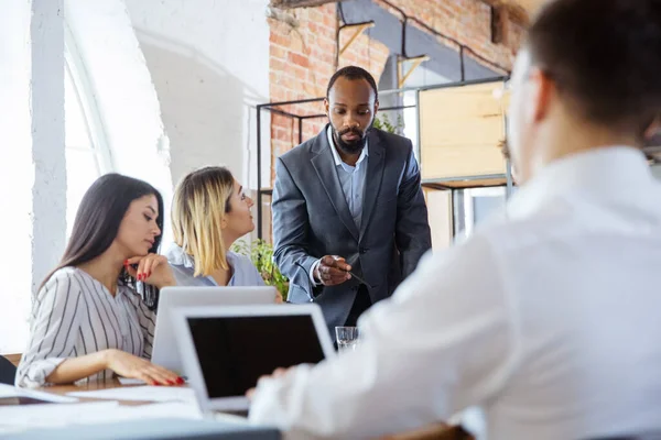 Diverso grupo de compañeros de trabajo que tienen una discusión informal en el cargo. Ejecutivos durante la discusión amistosa, informes mensuales, reunión creativa — Foto de Stock