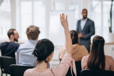 Erkek konuşmacı atölyede sunum yapıyor. Seyirci ya da konferans salonu. Tanınmayan katılımcıların arka görünümü.