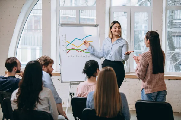 Vrouwelijke spreker die een presentatie geeft in de hal van de workshop. Publiek of conferentiezaal. Achteraanzicht van niet-erkende deelnemers. — Stockfoto