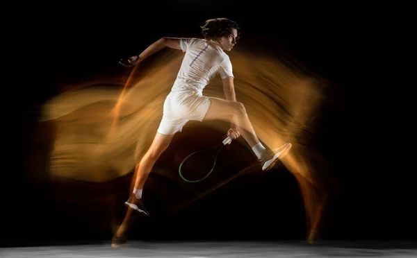 Jovem esportista profissional caucasiano jogando tênis em fundo preto em luz mista — Fotografia de Stock