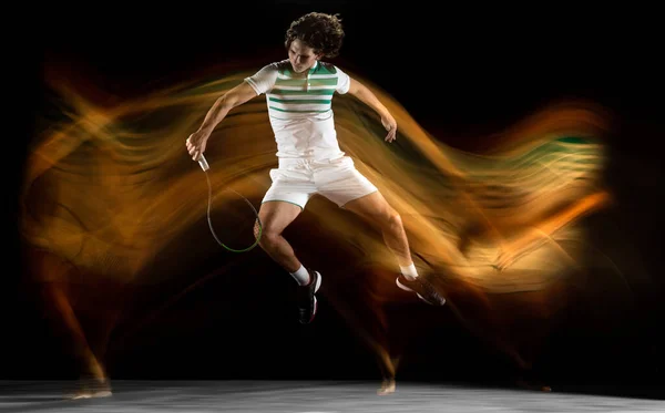 Fiatal kaukázusi profi sportoló teniszezik fekete alapon vegyes fényben — Stock Fotó