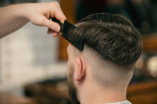 El primer plano del cliente del barbero maestro, el estilista durante el cuidado del peinado. Ocupación profesional, concepto de belleza masculino — Foto de Stock