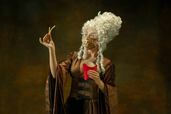 Portrait of medieval young woman in vintage clothes and golden face mask on dark background. — Stock Photo, Image