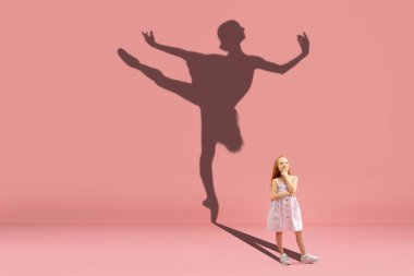 Çocukluk ve büyük ve ünlü bir gelecek hayal etmek. Kızlı kavramsal görüntü ve mercan pembe arka planda dans eden fit balerin gölgesi.