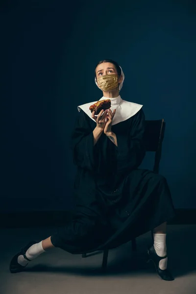 Ortaçağ genç bayanı, eski giysiler içinde bir rahibe ve koyu mavi arka planda altın maske takıyor. Dönem karşılaştırması kavramı, covid 'den koruma — Stok fotoğraf