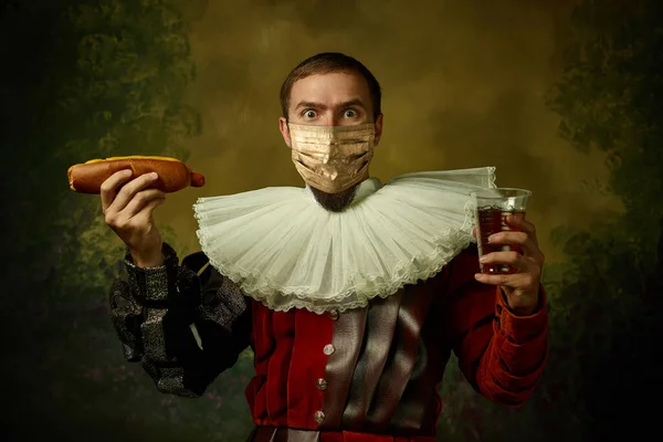 Πορτρέτο του μεσαιωνικού νέου άνδρα σε vintage ρούχα και χρυσή μάσκα προσώπου στέκεται σε σκούρο φόντο. — Φωτογραφία Αρχείου