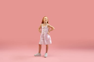 Çocukluk ve büyük ve ünlü bir gelecek hayal etmek. Mercan pembe arka planda izole edilmiş güzel uzun saçlı kız.