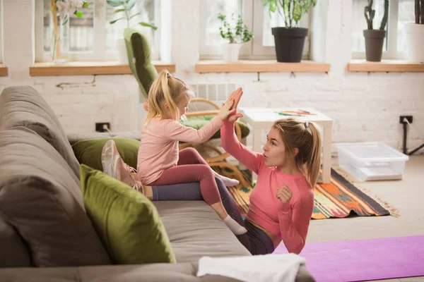 Ung kvinne som trener trening, aerob yoga hjemme, sportslig livsstil. Bli aktiv med barnet som leker, gymmen hjemme. – stockfoto