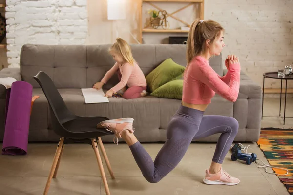 Jonge vrouw fitness, aerobic, yoga thuis, sportieve levensstijl. Actief met haar kind spelen, home gym. — Stockfoto