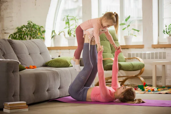 Spor yapan genç bir kadın, aerobik, evde yoga, spor yaşam tarzı. Çocuğuyla oynarken, evde spor yaparken.. — Stok fotoğraf