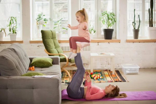 Spor yapan genç bir kadın, aerobik, evde yoga, spor yaşam tarzı. Çocuğuyla oynarken, evde spor yaparken.. — Stok fotoğraf