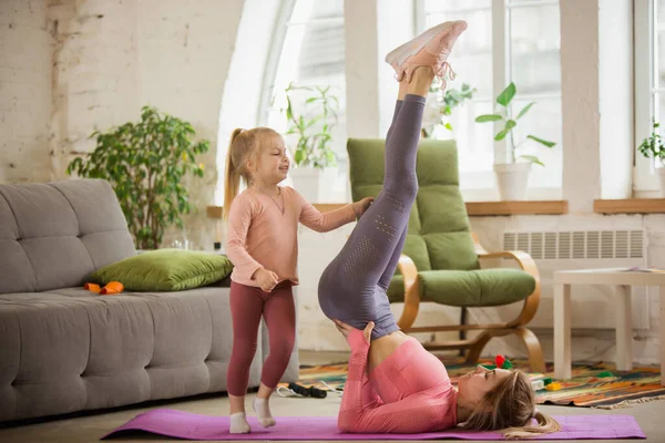 Spor yapan genç bir kadın, aerobik, evde yoga, spor yaşam tarzı. Çocuğuyla oynarken, evde spor yaparken.. — Stok fotoğraf