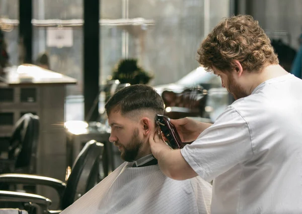 Primer peluquero maestro, estilista hace el peinado a chico, joven. Ocupación profesional, concepto de belleza masculino — Foto de Stock