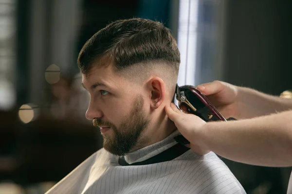 Närbild av klient master barberare, stylist under att få vård av frisyr. Yrke, manligt skönhetskoncept — Stockfoto