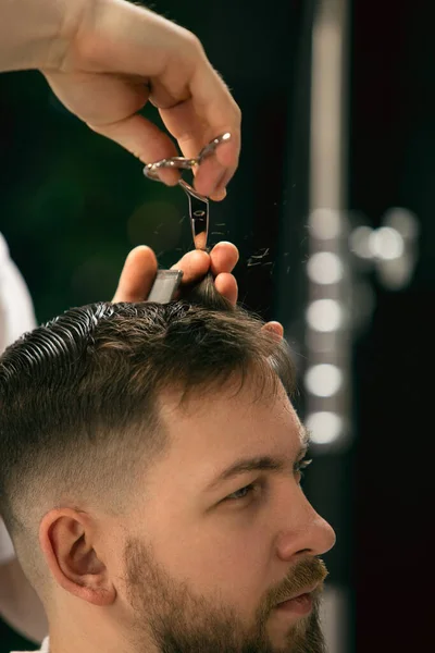 Primo piano del cliente del maestro barbiere, stilista durante la cura dell'acconciatura. Professione professionale, concetto di bellezza maschile — Foto Stock