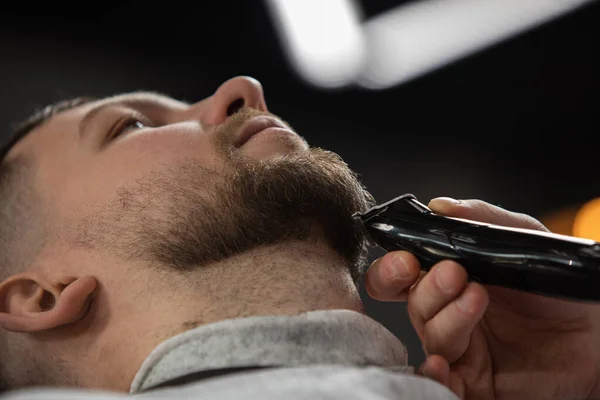 Großaufnahme vom Kunden des Friseurmeisters, Stylisten während der Pflege von Schnurrbart und Bart. Professionelle Beschäftigung, männliches Schönheitskonzept — Stockfoto