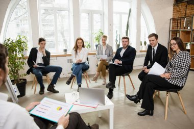 Erkek konuşmacı atölyede sunum yapıyor. Seyirci ya da konferans salonu. Katılımcıların ön görünümü.