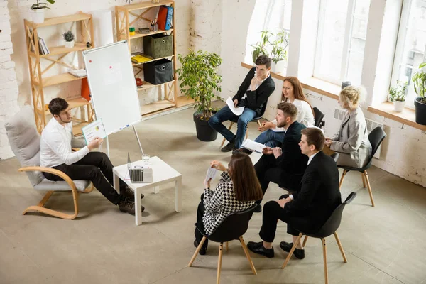 Ponente masculino dando presentación en salón en taller. Público o sala de conferencias. Vista de ángulo alto de participantes no reconocidos. — Foto de Stock