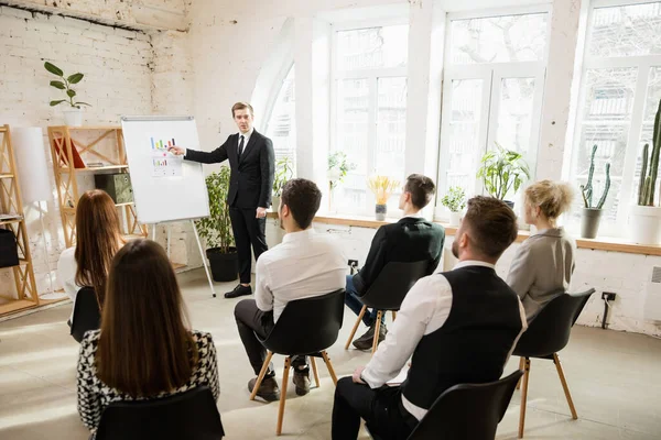 Conférencier masculin donnant une présentation dans le hall à l'atelier. Public ou salle de conférence. Vue arrière des participants non reconnus. — Photo