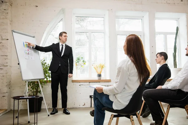 Ponente masculino dando presentación en salón en taller. Público o sala de conferencias. Vista lateral de participantes no reconocidos. — Foto de Stock