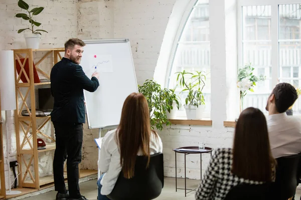 Conférencier masculin donnant une présentation dans le hall à l'atelier. Public ou salle de conférence. Vue arrière des participants non reconnus. — Photo