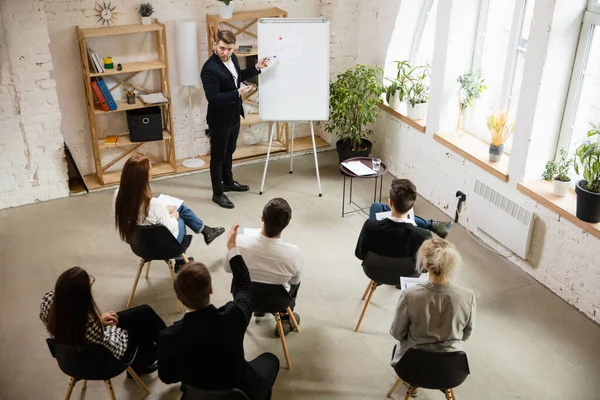 Male speaker giving presentation in hall at workshop. Audience or conference hall. High angle of unrecognized participants. — Stock Photo, Image