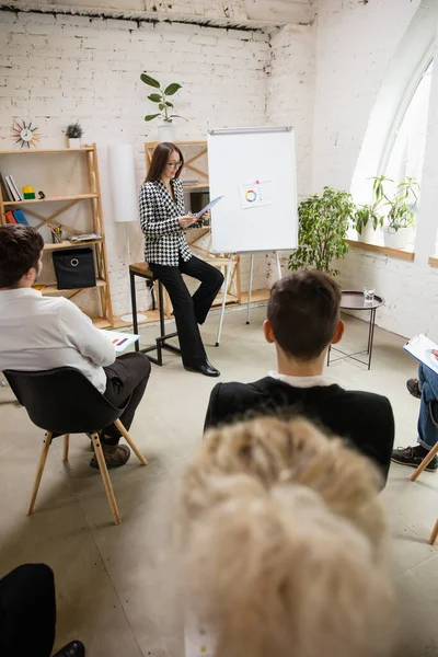 Ponente femenina dando presentación en salón en taller. Público o sala de conferencias. Vista trasera de participantes no reconocidos. — Foto de Stock