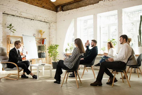 Mužský řečník přednáší v hale na workshopu. Audience nebo konferenční sál. Boční pohled nerozpoznaných účastníků. — Stock fotografie