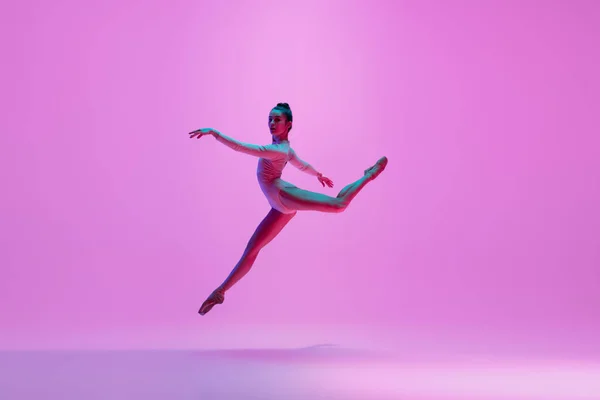 Jeune et gracieuse danseuse de ballet isolée sur fond de studio rose au néon. Art, mouvement, action, flexibilité, concept d'inspiration. — Photo