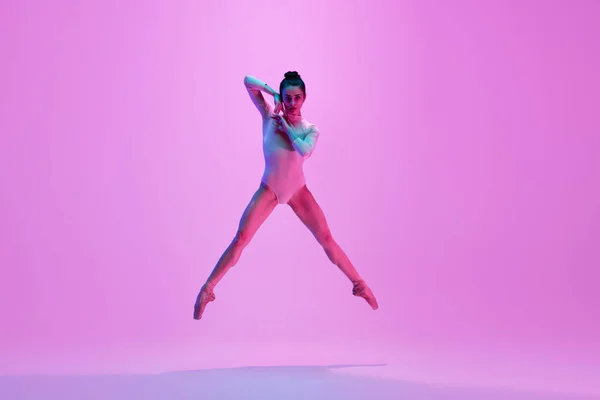 Fiatal és kecses balett táncos elszigetelt rózsaszín stúdió háttérben neon fényben. Művészet, mozgás, cselekvés, rugalmasság, inspiráció. — Stock Fotó