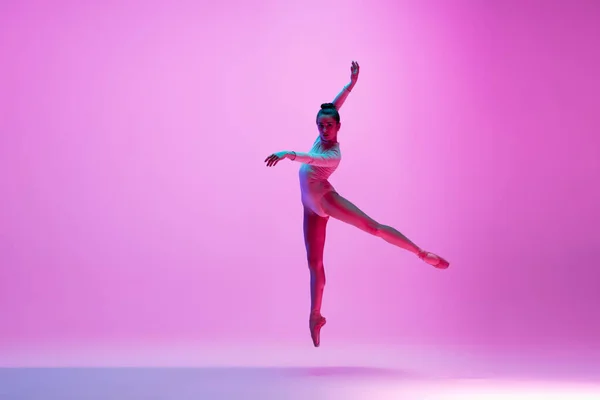 Jonge en sierlijke balletdanser geïsoleerd op roze studioachtergrond in neonlicht. Kunst, beweging, actie, flexibiliteit, inspiratie. — Stockfoto