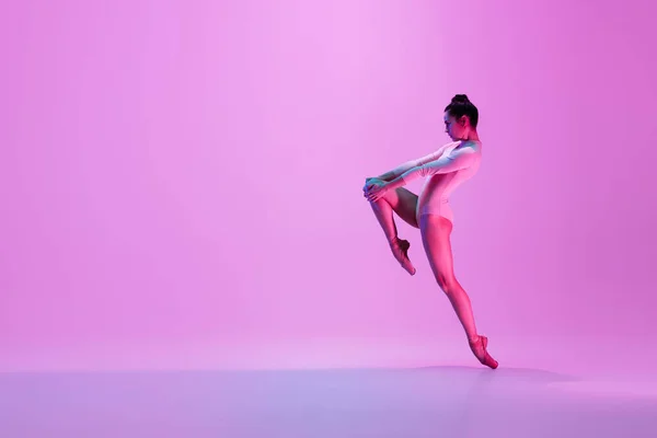 年轻而优雅的芭蕾舞演员在霓虹灯下被隔离在粉红色的工作室背景下.艺术、运动、动作、灵活性、灵感概念. — 图库照片