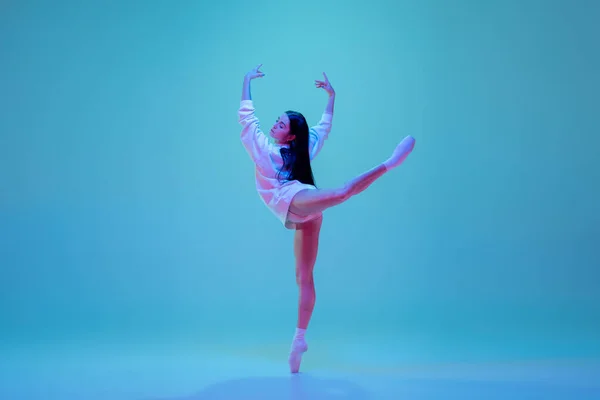 Jovem e graciosa dançarina de balé isolado em fundo estúdio azul em luz de néon. Arte, movimento, ação, flexibilidade, conceito de inspiração. — Fotografia de Stock