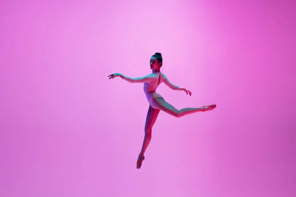 年轻而优雅的芭蕾舞演员在霓虹灯下被隔离在粉红色的工作室背景下.艺术、运动、动作、灵活性、灵感概念. — 图库照片