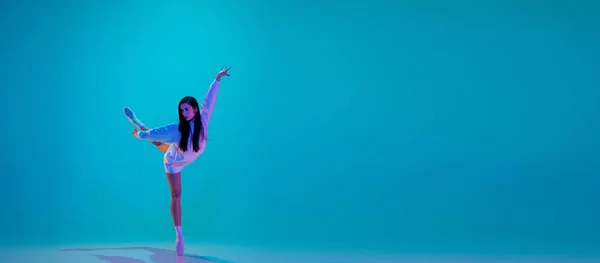Giovane e graziosa ballerina isolata su sfondo blu studio in luce al neon. Arte, movimento, azione, flessibilità, concetto di ispirazione. — Foto Stock