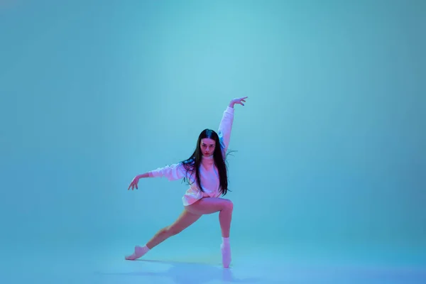 Jonge en sierlijke balletdanser geïsoleerd op blauwe studioachtergrond in neonlicht. Kunst, beweging, actie, flexibiliteit, inspiratie. — Stockfoto