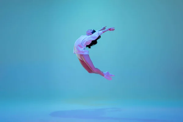 ネオンの光の中でブルーのスタジオの背景に隔離された若く優雅なバレエダンサー。芸術、運動、行動、柔軟性、インスピレーションの概念. — ストック写真