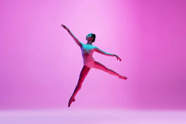 Jonge en sierlijke balletdanser geïsoleerd op roze studioachtergrond in neonlicht. Kunst, beweging, actie, flexibiliteit, inspiratie. — Stockfoto