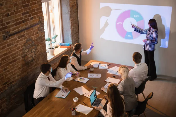 Vrouwelijke spreker die een presentatie geeft in de hal van de workshop. Publiek of conferentiezaal. Deelnemers, collega 's die aan tafel luisteren. — Stockfoto