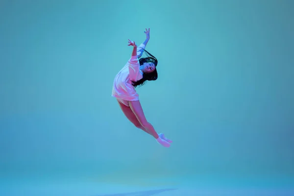 Jonge en sierlijke balletdanser geïsoleerd op blauwe studioachtergrond in neonlicht. Kunst, beweging, actie, flexibiliteit, inspiratie. — Stockfoto