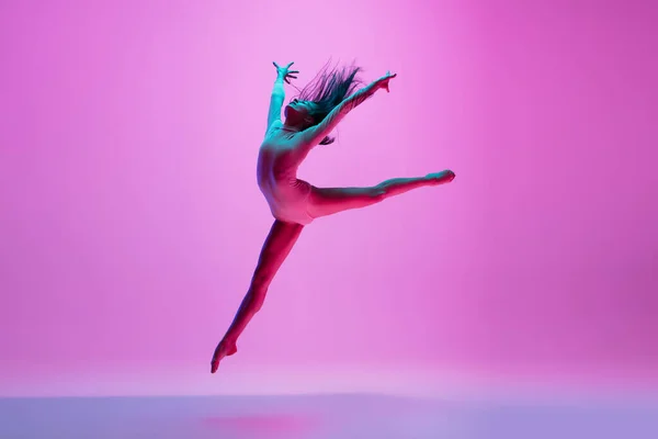 Jonge en sierlijke balletdanser geïsoleerd op roze studioachtergrond in neonlicht. Kunst, beweging, actie, flexibiliteit, inspiratie. — Stockfoto