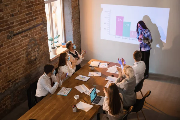 Reproduktorka přednáší v hale na workshopu. Audience nebo konferenční sál. Účastníci, spolupracovníci, kteří poslouchají u stolu. — Stock fotografie