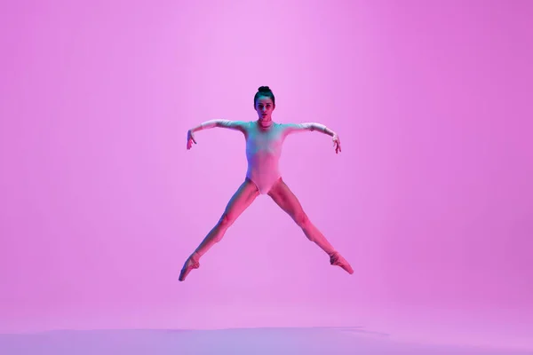 Jeune et gracieuse danseuse de ballet isolée sur fond de studio rose au néon. Art, mouvement, action, flexibilité, concept d'inspiration. — Photo