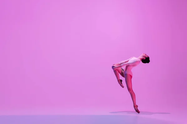 Jovem e graciosa dançarina de balé isolado no fundo do estúdio rosa em luz de néon. Arte, movimento, ação, flexibilidade, conceito de inspiração. — Fotografia de Stock